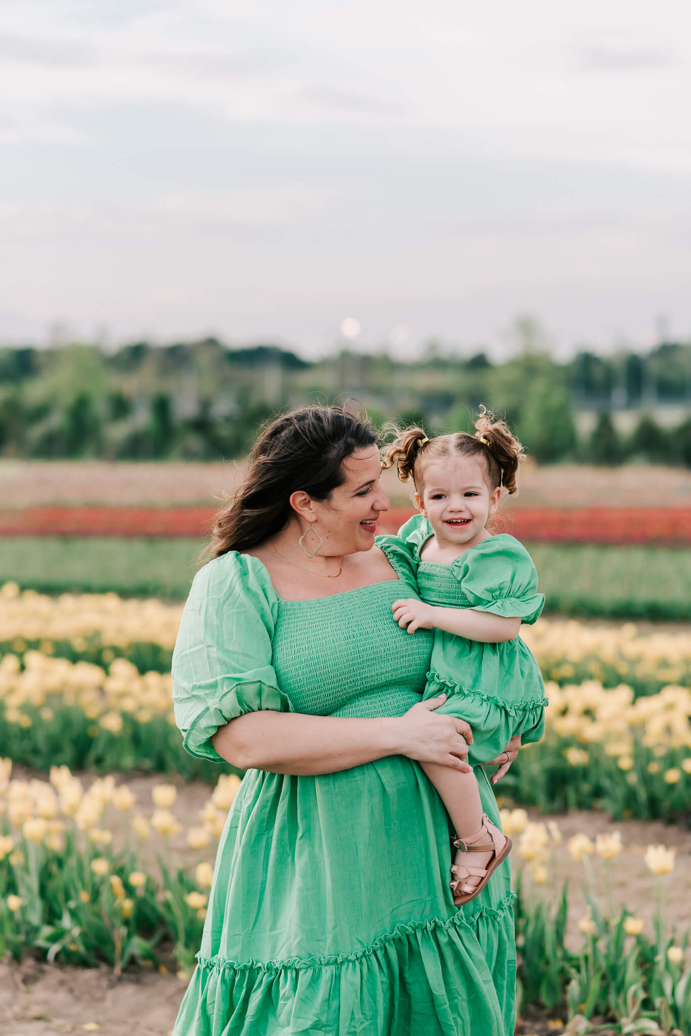 mother holding daughter in matching green dresses and laughing, touch therapeutic massage