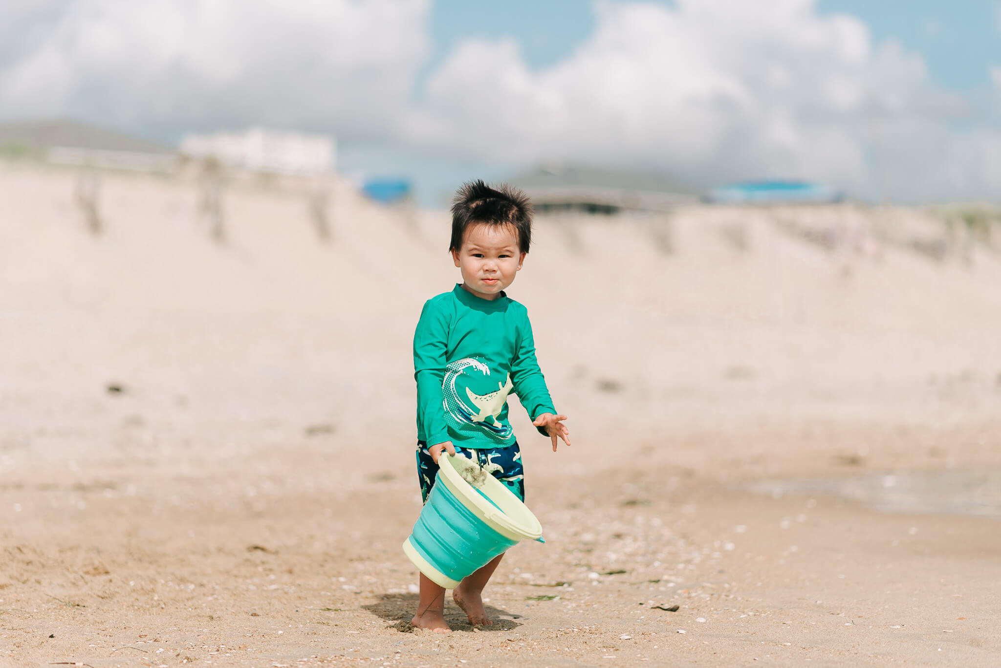 toddler holding a green bucket at a sandy beach, water parks in northern virginia