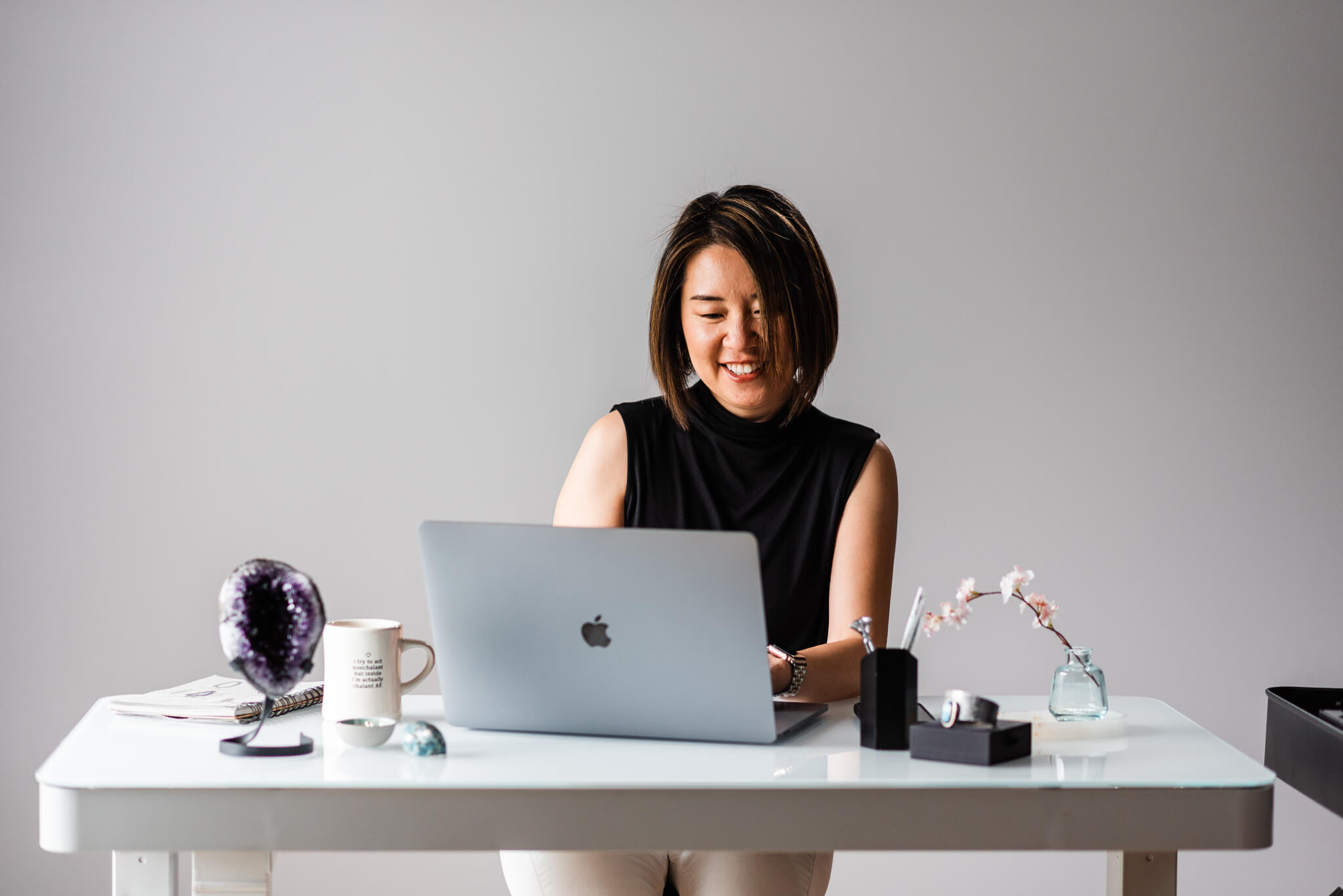 An Asian woman in her late 40s wearing a black blouse in front of her laptop doing work, Showit Website Templates for Photographers