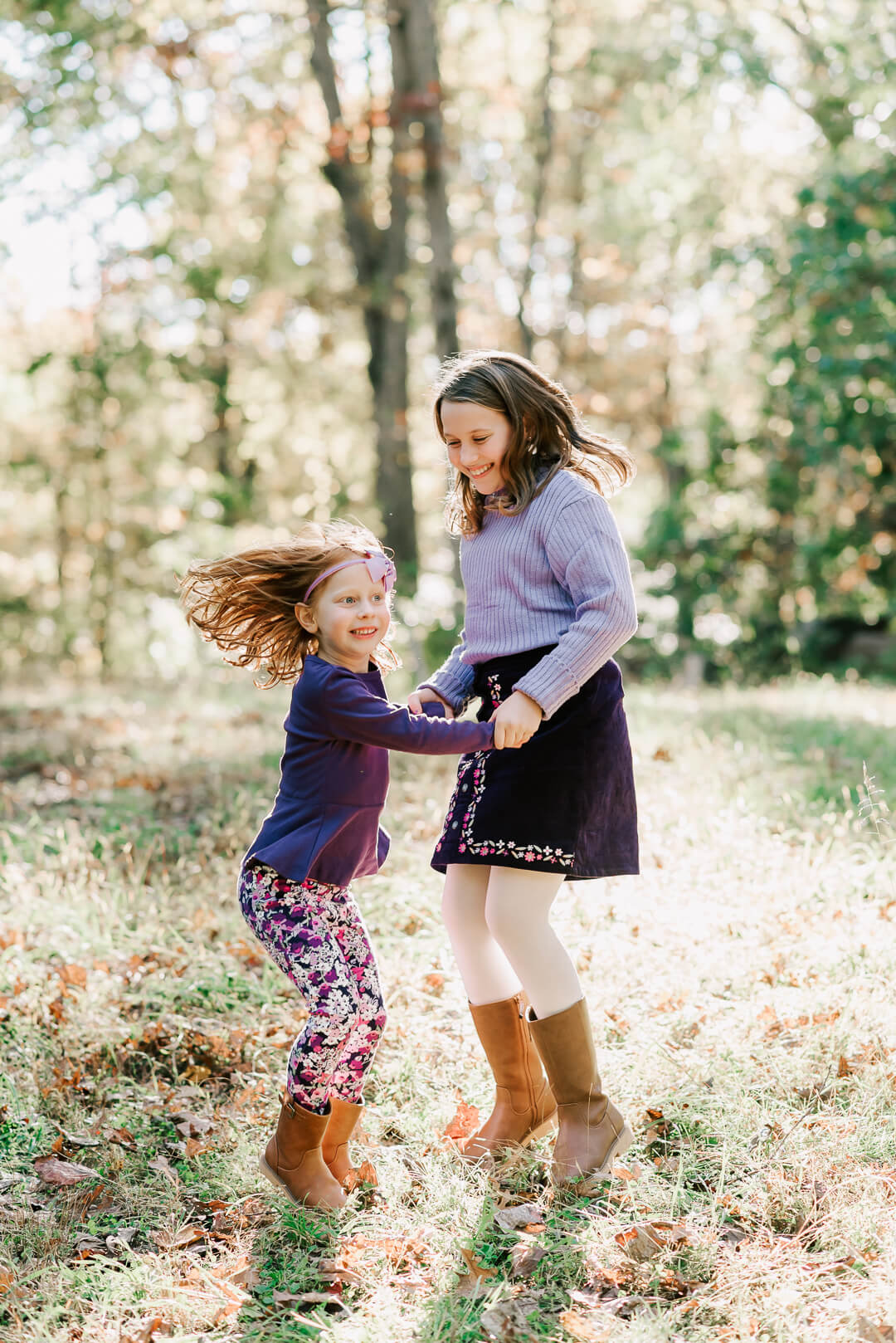 Two young sisters dance and play in purple outfits in a forest field after visiting einstein pediatrics