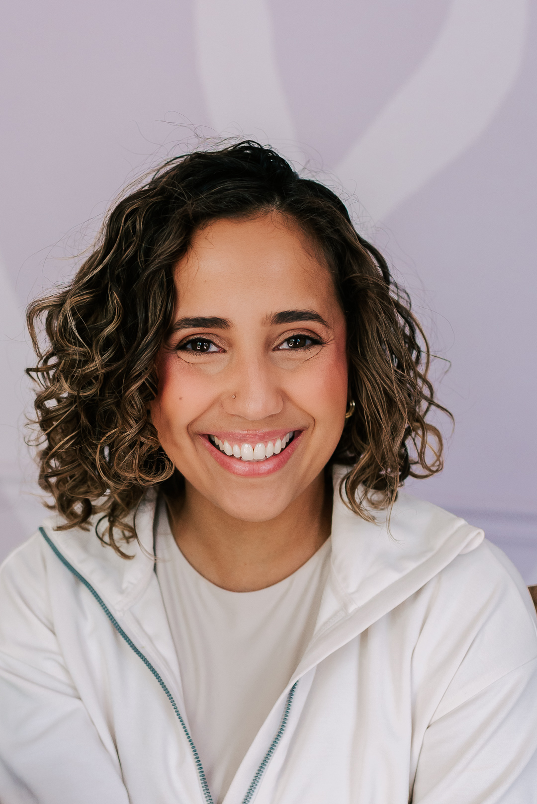 headshot of Two Can Grow owner smiling and wearing a sand shirt under a white pullover