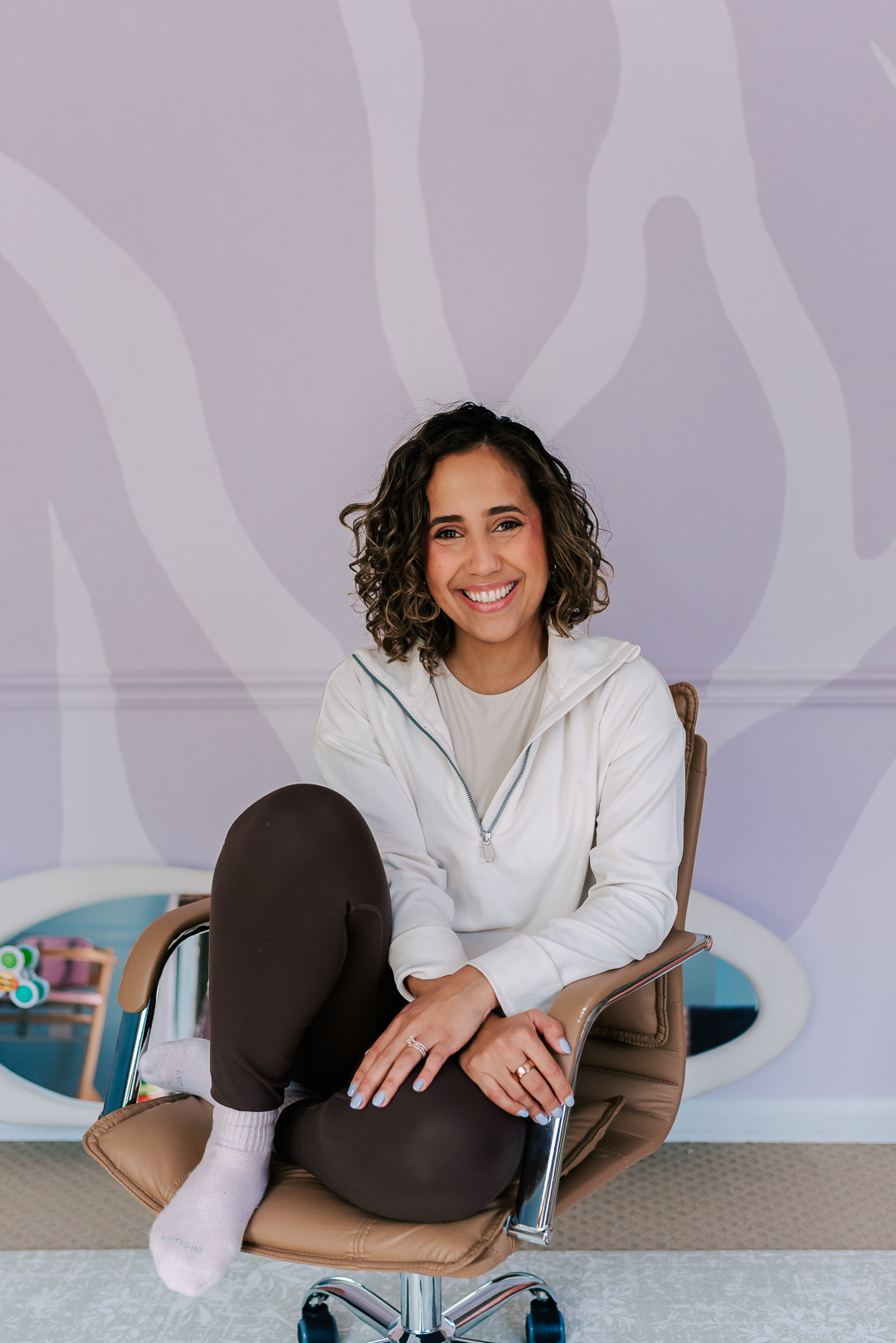 Woman with curly hair sitting on an office chair in her Two Can Grow office space in Vienna VA